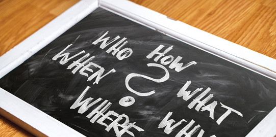 Fragen Eine Tafel mit den Fragen "What", "Why", "When", "Who", "Where", "How"