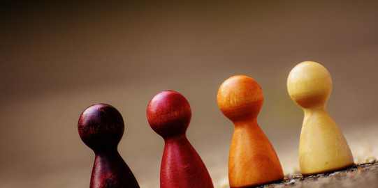 Play Stone Vier Spielsteine in verschiedenen warmen Tönen stehen nebeneinander.