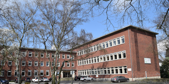 Das Gebäude der DAPF. Bäume stehen vor einem Ziegelsteingebäude.