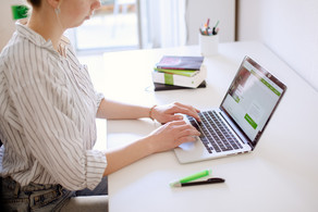 Arbeit am Laptop Am Schreibtisch sitzende Studentin tippt auf dem Laptop, daneben liegen Bücher und Stifte.